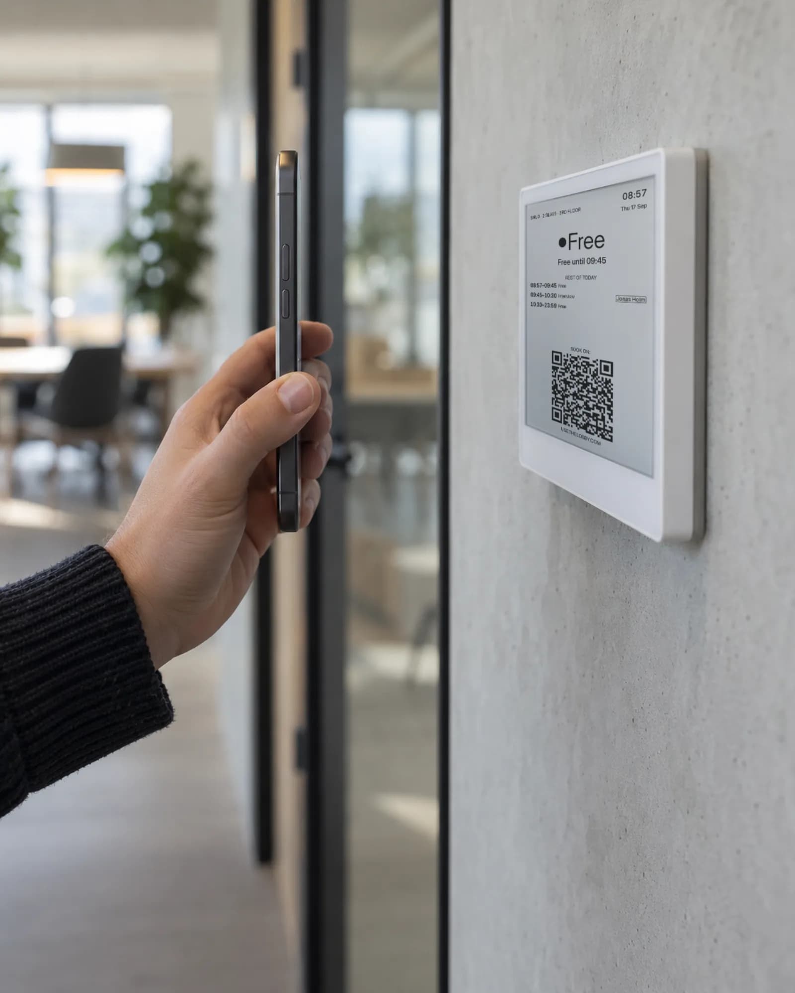 A phone camera pointed at the QR code on a Lobby room display