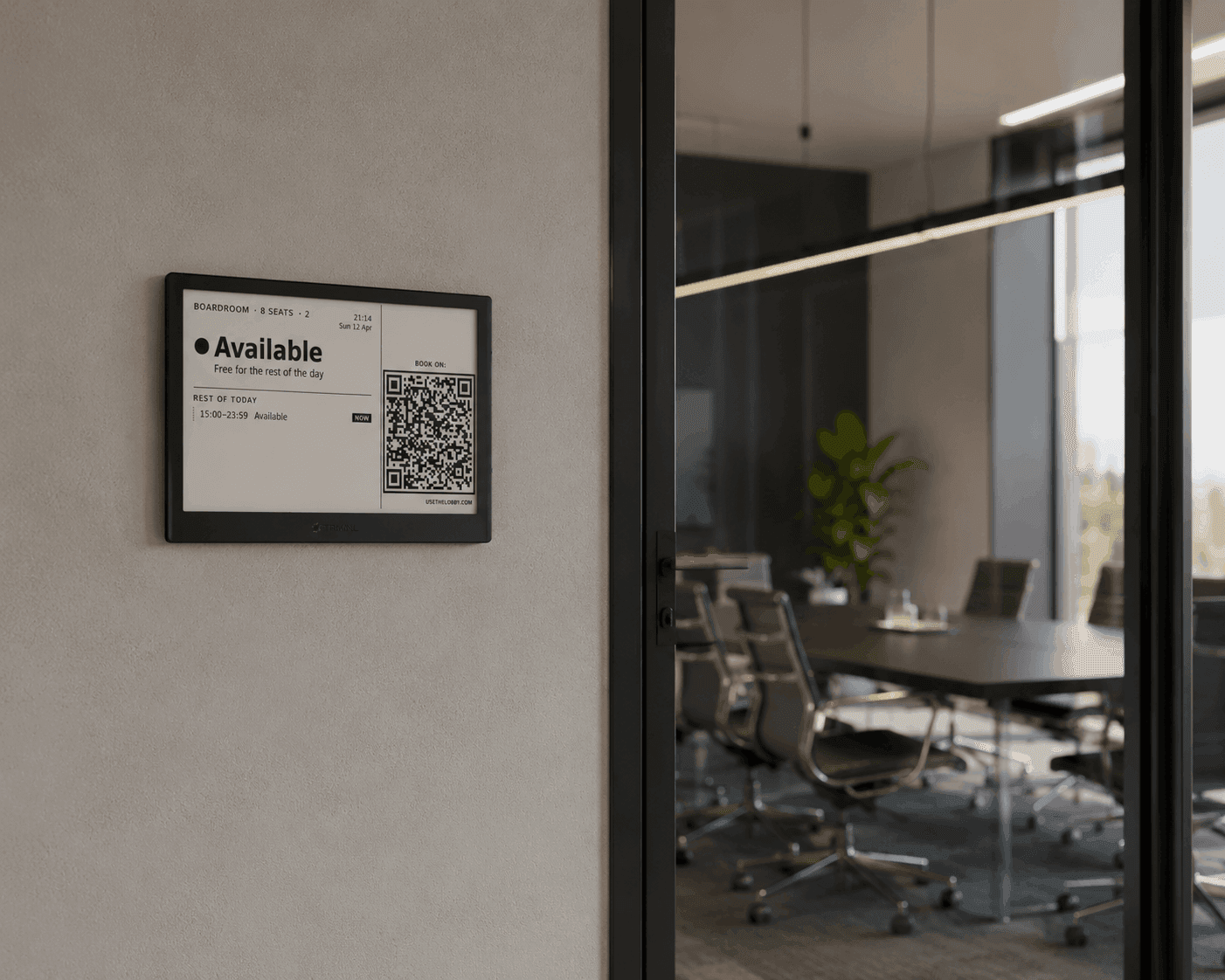 Lobby e-ink display mounted beside a glass meeting-room door showing Available